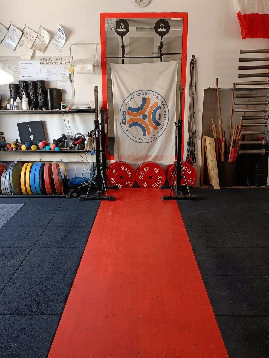 La pedana per la pesistica nella sala della Mak Training, con lo stendardo FIPE e i dischi bumper